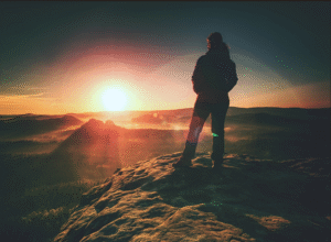 individual on mountain facing sun with belief 